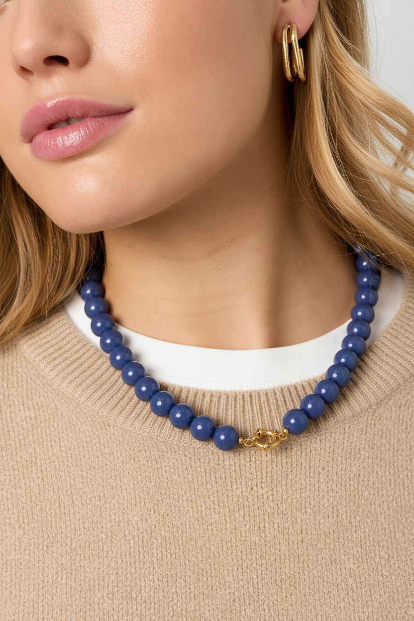 Blauwe kralenketting op beige wollen trui