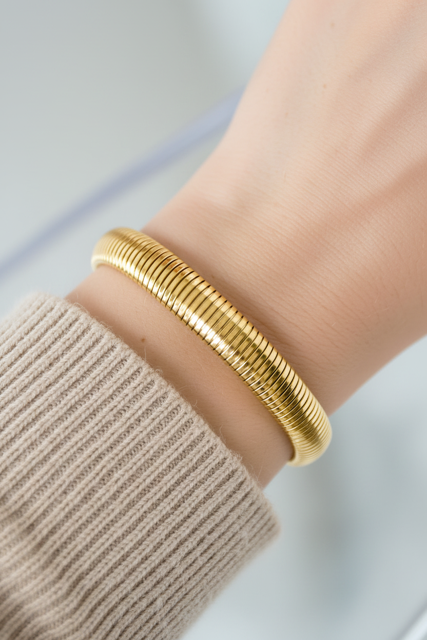 Gouden armband op pols met beige trui