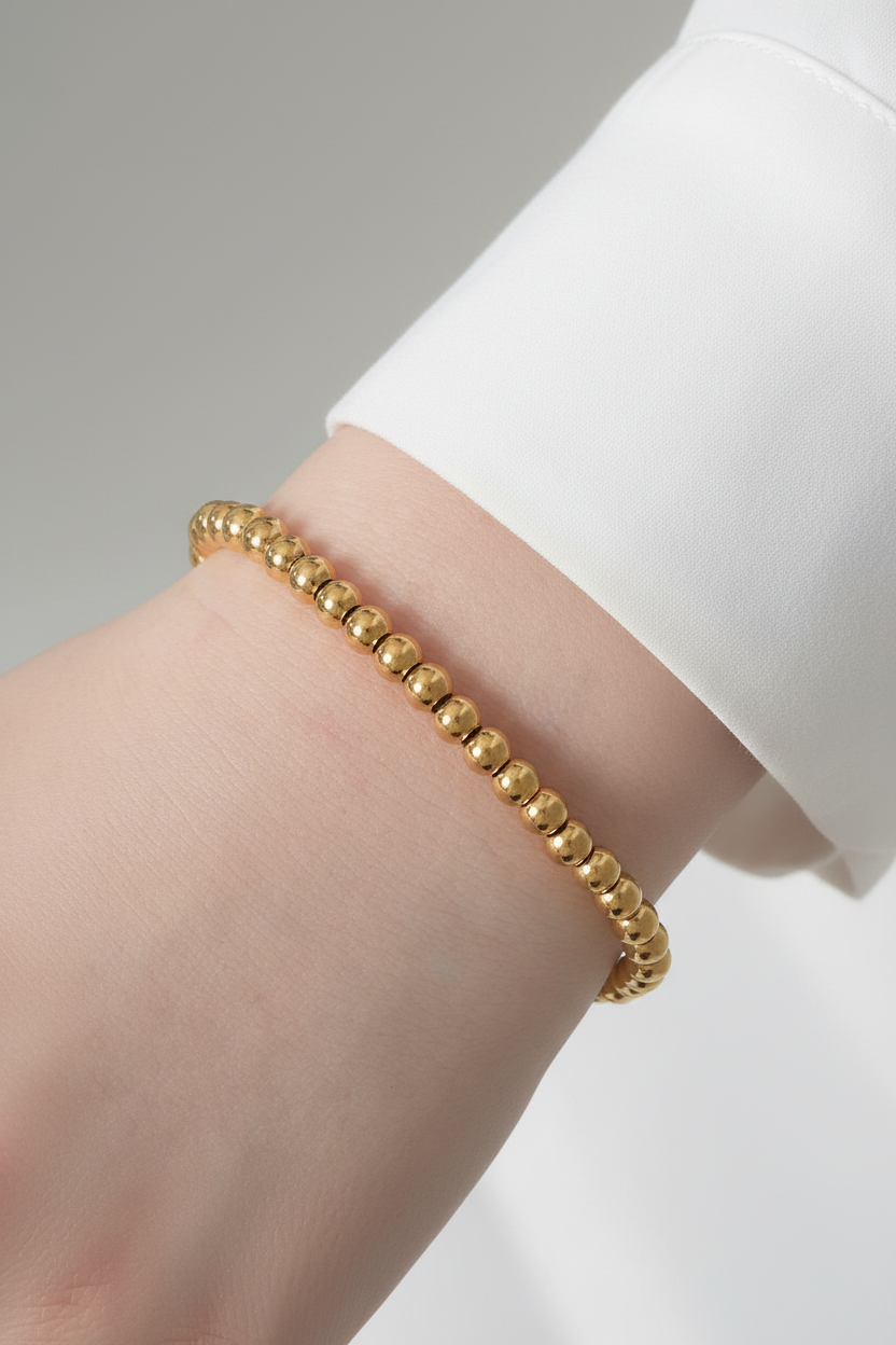 Gouden balletjes armband met witte blouse