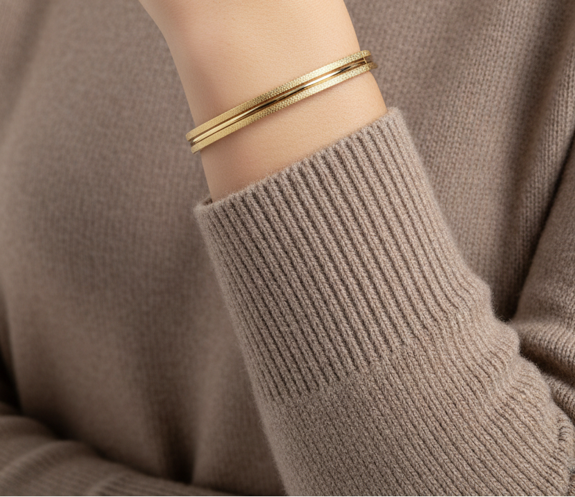 Gouden bangle op pols met taupe trui